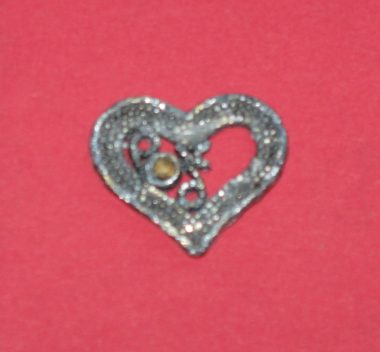 Heart Day | SMA News Today | A small silver heart charm with a gold stone in the center.