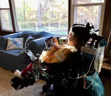 new home | SMA News Today | Halsey sits in her wheelchair next to large windows in her family's new home.